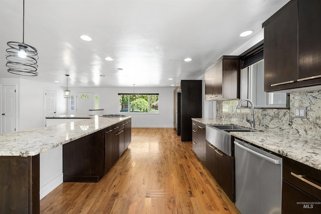 kitchen with appliances with stainless steel finishes, a spacious island, baseboards, tasteful backsplash, and a sink