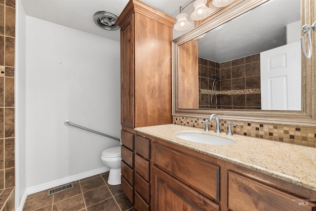 full bath featuring toilet, baseboards, tasteful backsplash, vanity, and a tile shower