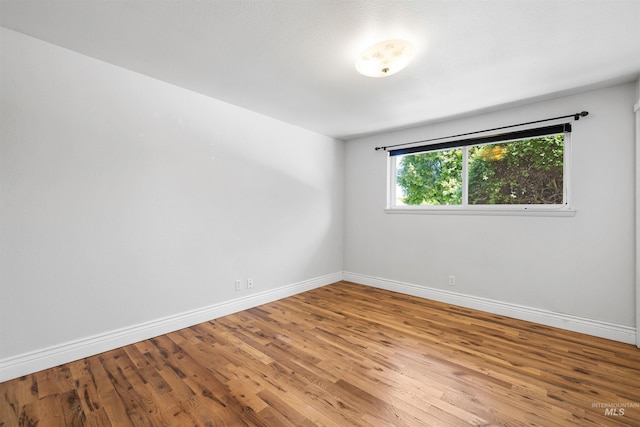 spare room with baseboards and wood finished floors