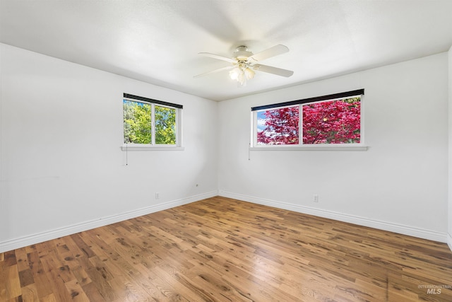 empty room featuring ceiling fan, baseboards, and wood finished floors
