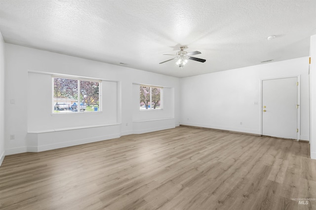 spare room with ceiling fan, light wood finished floors, a textured ceiling, and baseboards