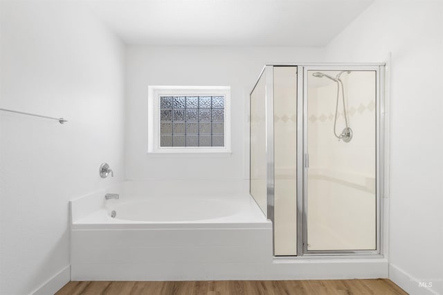 bathroom featuring wood finished floors, a stall shower, and a bath