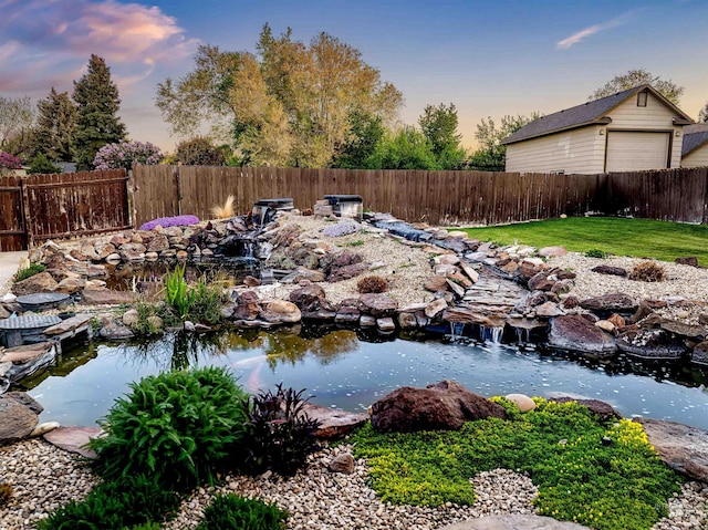 yard at dusk featuring a small pond