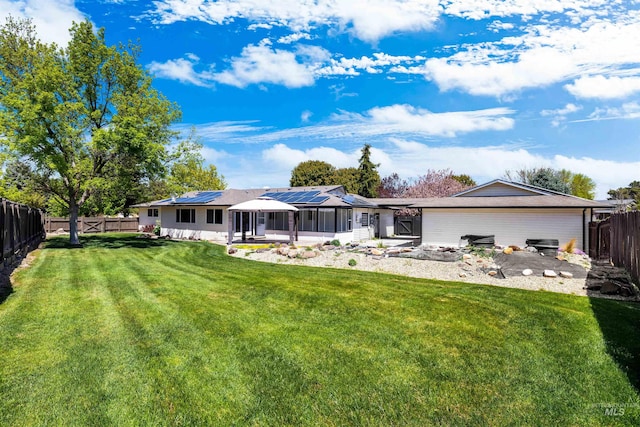 rear view of house with roof mounted solar panels and a sunroom