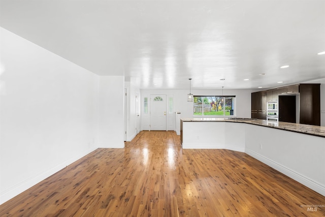 unfurnished living room with light wood-type flooring, baseboards, and recessed lighting