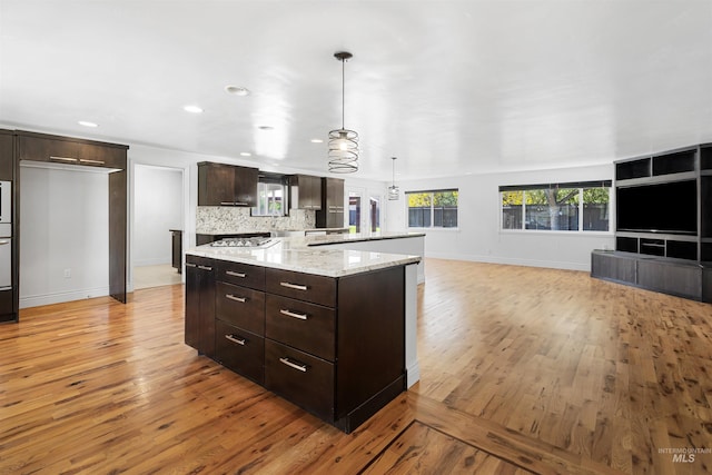 kitchen with baseboards, light wood-style floors, open floor plan, dark brown cabinetry, and a center island