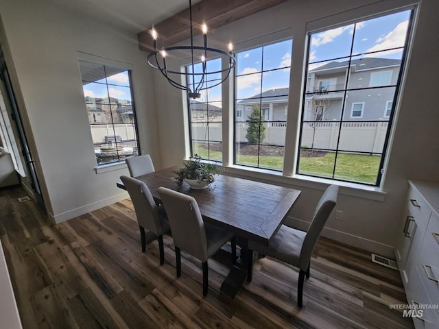 dining room with dark wood-type flooring, a wealth of natural light, an inviting chandelier, and baseboards