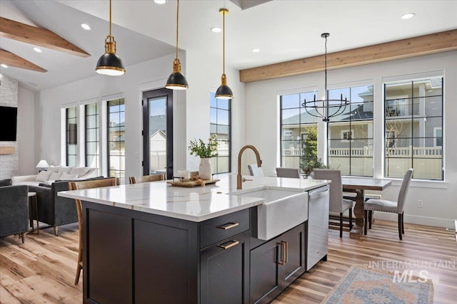 kitchen featuring open floor plan, light wood-type flooring, dishwasher, and a sink