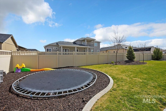 view of yard with a trampoline, a residential view, and a fenced backyard
