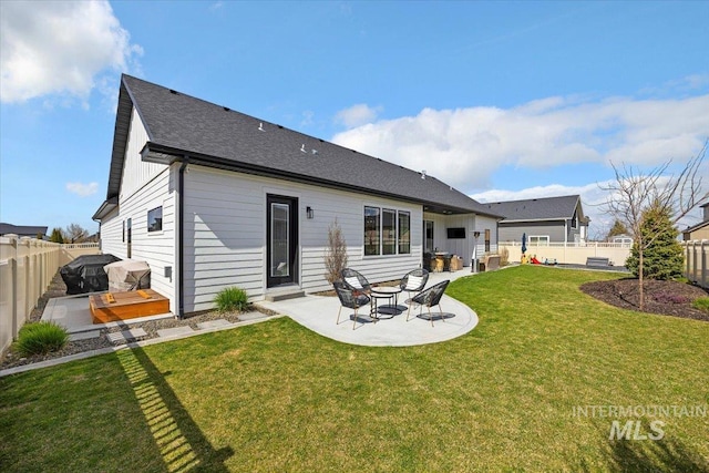 back of house with a patio, a yard, a fenced backyard, and roof with shingles