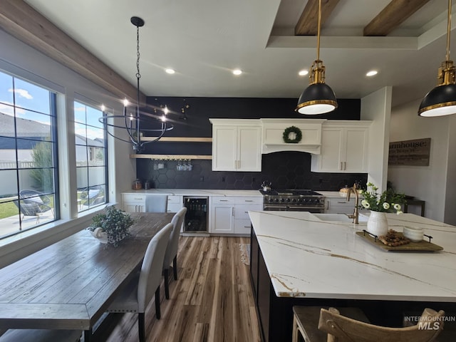 kitchen with white cabinetry, double oven range, wood finished floors, a sink, and beverage cooler