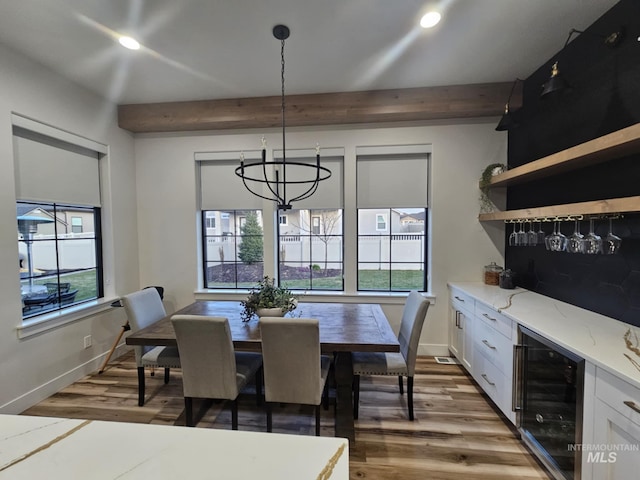 dining space with a bar, a chandelier, wine cooler, beamed ceiling, and wood finished floors