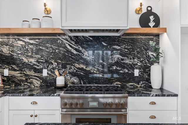 kitchen featuring white cabinets, range with two ovens, and dark stone countertops