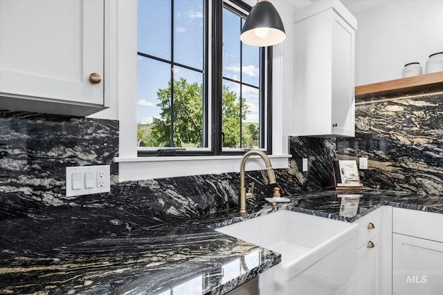 kitchen featuring backsplash, dark stone countertops, and white cabinetry