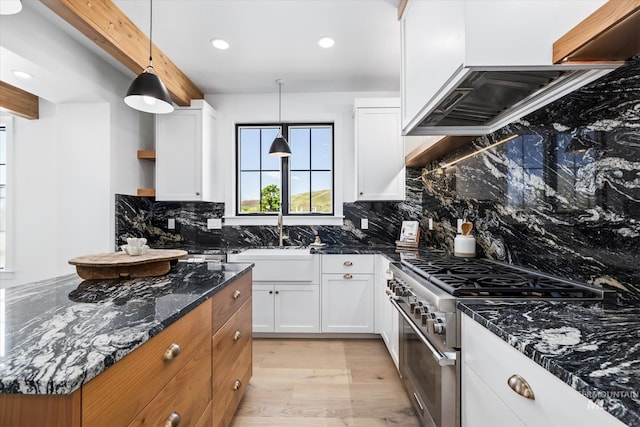 kitchen featuring high end stove, tasteful backsplash, light wood-type flooring, dark stone countertops, and white cabinets