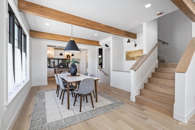 dining room with beamed ceiling, plenty of natural light, and light wood-type flooring