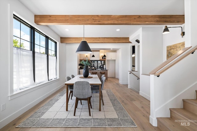 dining space with beamed ceiling and light hardwood / wood-style flooring