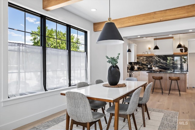 dining space with beam ceiling and light hardwood / wood-style floors