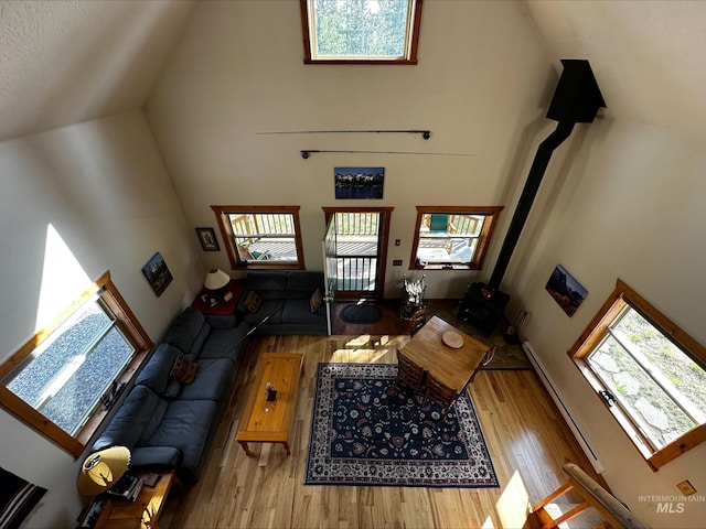 95 Valley Way, Stanley, ID 83278 - living area with a wood stove, high vaulted ceiling, wood finished floors, and a baseboard radiator