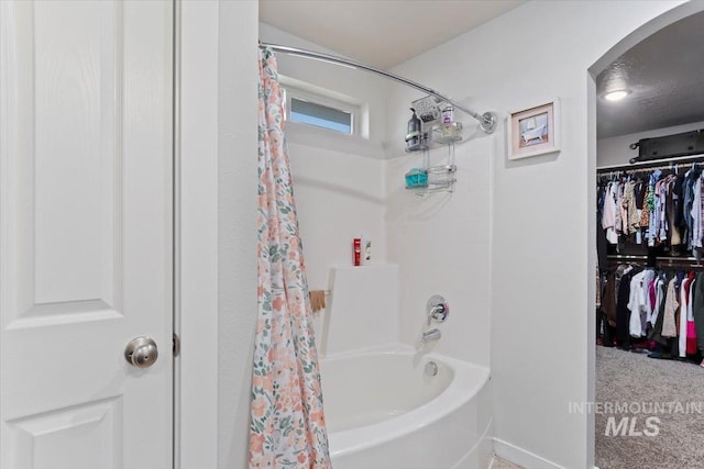 bathroom with a walk in closet and shower / bathtub combination with curtain