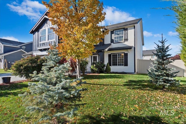 view of property hidden behind natural elements with fence, cooling unit, and a front yard