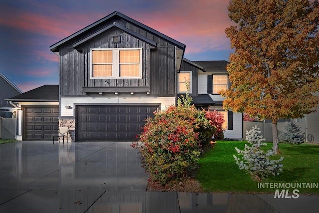view of front of home featuring an attached garage, board and batten siding, a yard, and concrete driveway