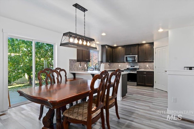 dining room with light wood-style floors, plenty of natural light, and recessed lighting