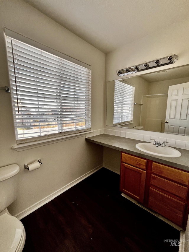 bathroom with toilet, a wealth of natural light, hardwood / wood-style flooring, and vanity