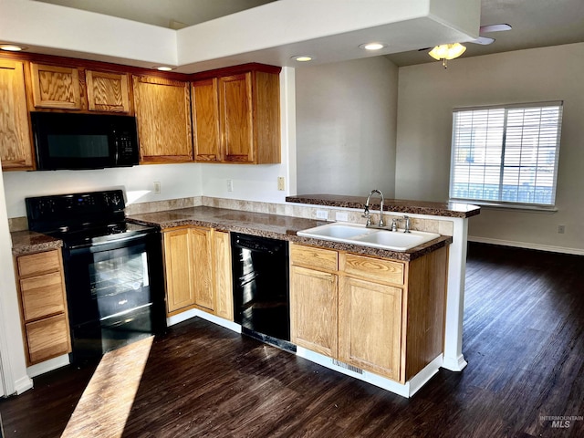 kitchen with sink, dark hardwood / wood-style floors, black appliances, and kitchen peninsula