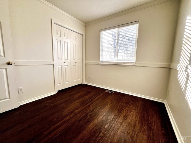 unfurnished bedroom featuring a closet, dark hardwood / wood-style floors, and ornamental molding