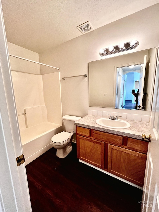 full bathroom featuring tub / shower combination, a textured ceiling, vanity, toilet, and hardwood / wood-style flooring