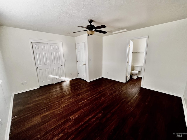 unfurnished bedroom featuring ceiling fan, a textured ceiling, ensuite bathroom, and dark hardwood / wood-style floors