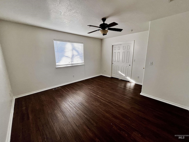 empty room featuring ceiling fan, dark hardwood / wood-style flooring, and a textured ceiling