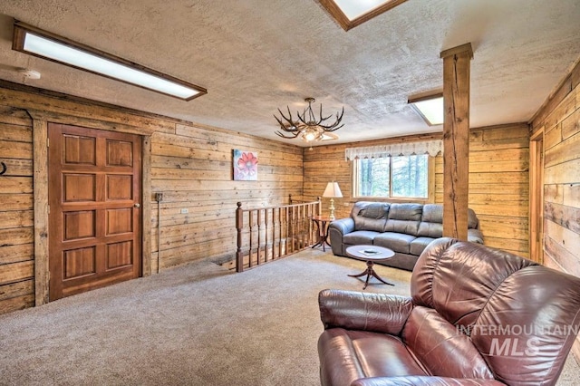 living room featuring carpet, a textured ceiling, wooden walls, and an inviting chandelier