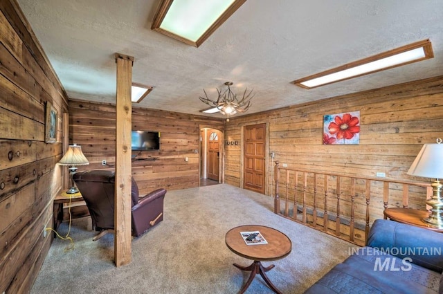 living room with carpet flooring, wood walls, and a textured ceiling