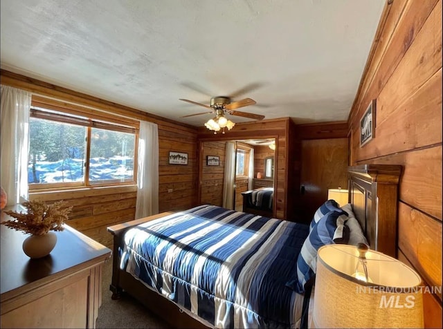 bedroom featuring ceiling fan, dark carpet, and wooden walls