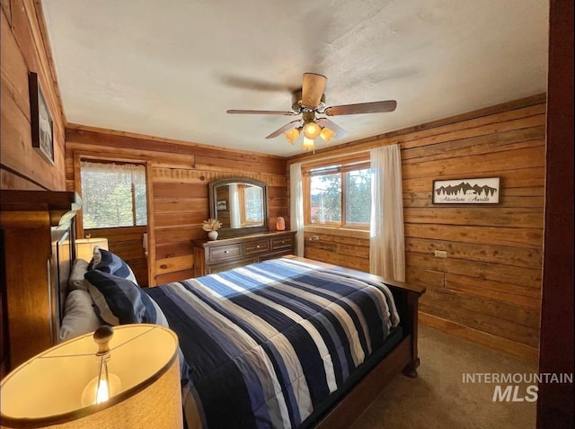 carpeted bedroom featuring ceiling fan and wood walls