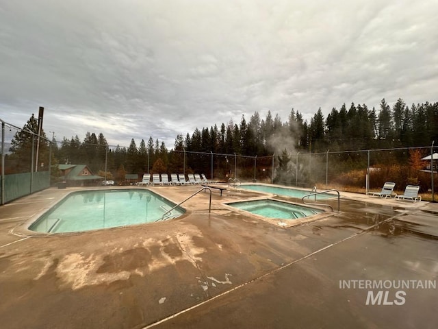 view of swimming pool featuring a community hot tub and a patio