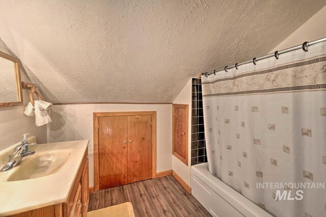 bathroom featuring shower / bathtub combination with curtain, vanity, vaulted ceiling, and hardwood / wood-style flooring