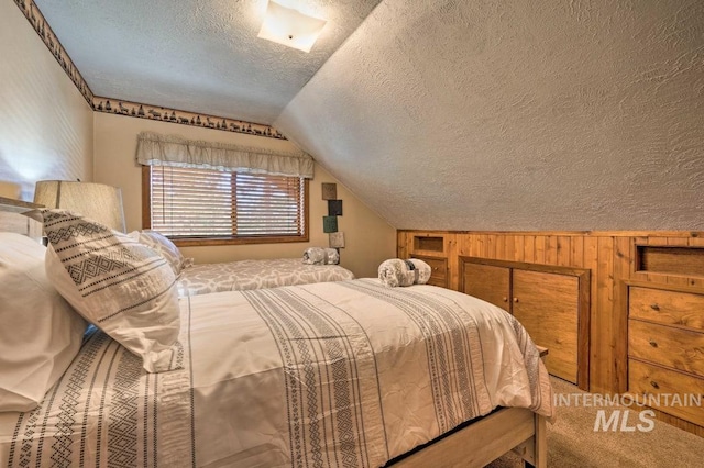 bedroom featuring a textured ceiling, wooden walls, and vaulted ceiling