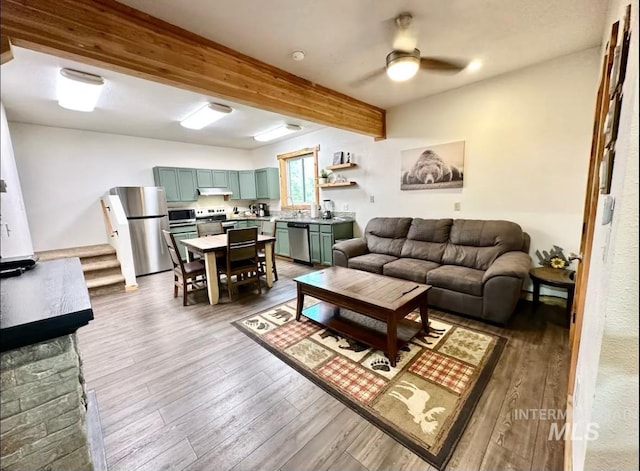 living room with wood-type flooring, ceiling fan, and beam ceiling