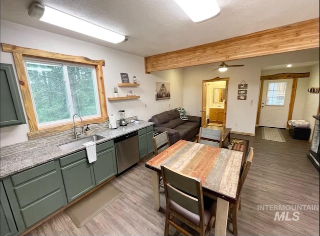 kitchen featuring stainless steel dishwasher, light stone counters, sink, and green cabinetry