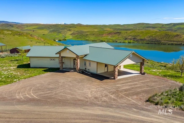 view of front of home featuring driveway, a water and mountain view, metal roof, and a carport