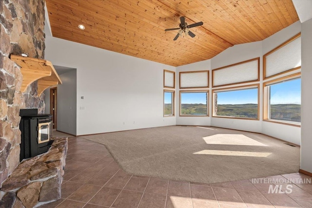 unfurnished living room featuring carpet floors, tile patterned floors, high vaulted ceiling, a wood stove, and ceiling fan