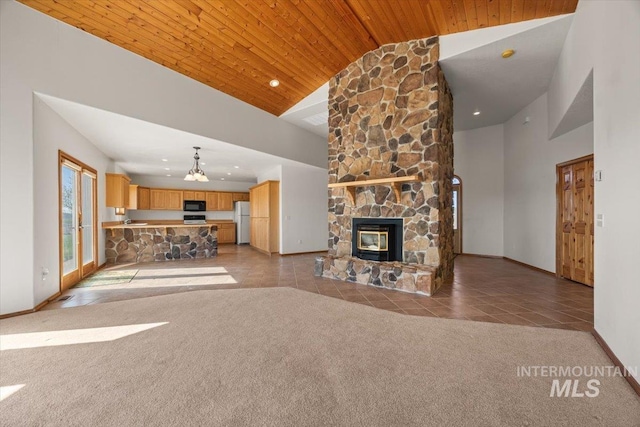 unfurnished living room featuring high vaulted ceiling, carpet flooring, a stone fireplace, tile patterned floors, and baseboards