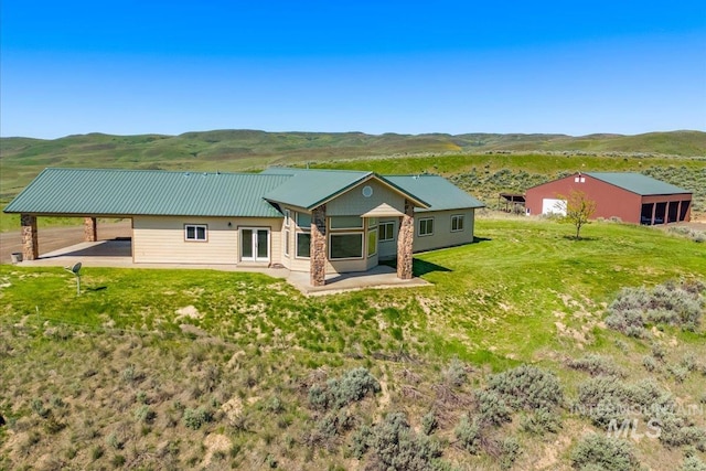 rear view of property featuring a patio, a mountain view, metal roof, and a yard