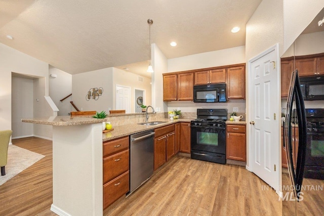 kitchen featuring pendant lighting, black appliances, sink, a kitchen breakfast bar, and kitchen peninsula