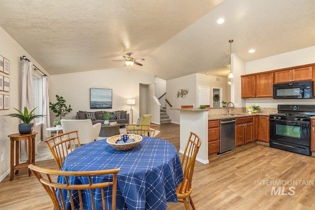 dining space featuring vaulted ceiling, sink, ceiling fan, light hardwood / wood-style floors, and a textured ceiling