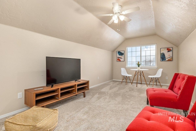 carpeted living room featuring ceiling fan, vaulted ceiling, and a textured ceiling