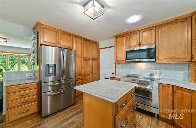 14 Cougar Ln, Boise, ID 83716 - kitchen featuring appliances with stainless steel finishes, wood finished floors, brown cabinets, decorative backsplash, and a kitchen island